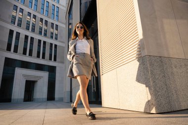 İş kadını kahve içiyor. Profesyonel avukat ya da benzeri açık havada tek kullanımlık kağıt bardak tutarken mutlu. Beyaz iş kadını dışarıda mutlu gülümsüyor..