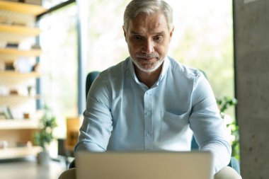 Gülümseyen işadamı ofis lobisinde oturmuş dizüstü bilgisayarla çalışıyor. Ofis lobisinde çalışan bir erkek işadamı..