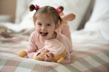 Pijama giymiş sevimli küçük bir kız evde oyuncak tavşanına sarılıyor, mutlu çocukluk konsepti, kapalı alanda.
