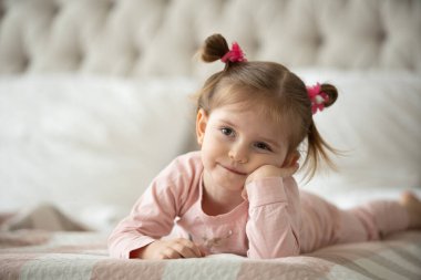 Pijama giymiş sevimli küçük bir kız evde oyuncak tavşanına sarılıyor, mutlu çocukluk konsepti, kapalı alanda.