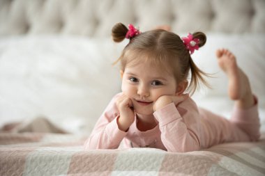 Pijama giymiş sevimli küçük bir kız evde oyuncak tavşanına sarılıyor, mutlu çocukluk konsepti, kapalı alanda.