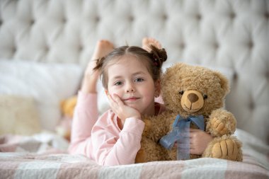 Pijama giymiş sevimli küçük bir kız evde oyuncak tavşanına sarılıyor, mutlu çocukluk konsepti, kapalı alanda.