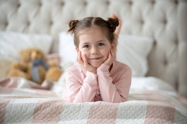 Pijama giymiş sevimli küçük bir kız evde oyuncak tavşanına sarılıyor, mutlu çocukluk konsepti, kapalı alanda.