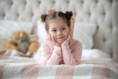 Pijama giymiş sevimli küçük bir kız evde oyuncak tavşanına sarılıyor, mutlu çocukluk konsepti, kapalı alanda.