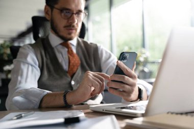 İşle meşgul. Ofiste oturan akıllı telefonu tutan gülümseyen bir işadamı. Cep telefonu uygulamaları kullanan orta yaşlı bir yönetici. Dijital teknoloji uygulamaları ve iş geliştirme çözümleri
