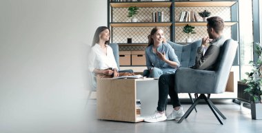 İlgilenen mutlu genç meslektaşlar koltuklarda oturuyor, patron takım liderini dinliyor, toplantı brifinginde çalışma sorunlarını anlatıyor, uluslararası şirket işbirliği