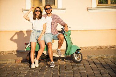 Aşık bir çift gün batımında bir motosikletin yanında duruyor. Yakışıklı adam ve genç seksi kadın seyahati. Seyahat, romantizm, eğlence. Macera ve tatil kavramı.