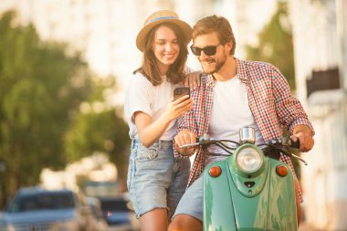 Seyahat eden genç bir çift, akıllı telefondan güzergaha bakıyor, şehirdeki online haritaları okuyor. Seyahat, romantizm, eğlence. Macera ve tatil kavramı.