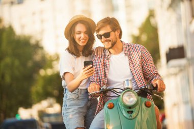Seyahat eden genç bir çift, akıllı telefondan güzergaha bakıyor, şehirdeki online haritaları okuyor. Seyahat, romantizm, eğlence. Macera ve tatil kavramı.