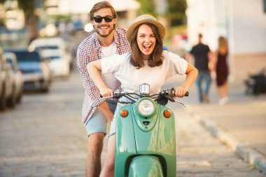 Kasabada scooter süren gülen bir çift. Motosiklet süren bir adam. Macera ve tatil kavramı
