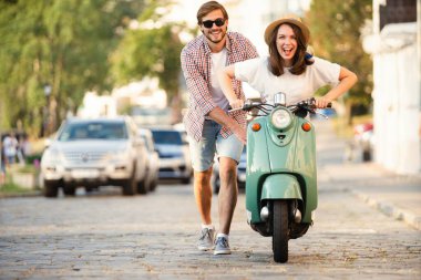 Kasabada scooter süren gülen bir çift. Motosiklet süren bir adam. Macera ve tatil kavramı