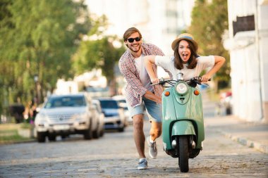 Kasabada scooter süren gülen bir çift. Motosiklet süren bir adam. Macera ve tatil kavramı