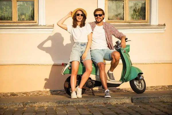 Aşık bir çift gün batımında bir motosikletin yanında duruyor. Yakışıklı adam ve genç seksi kadın seyahati. Seyahat, romantizm, eğlence. Macera ve tatil kavramı.