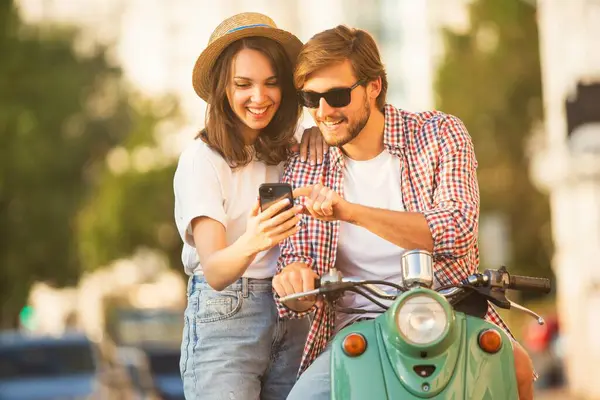 Seyahat eden genç bir çift, akıllı telefondan güzergaha bakıyor, şehirdeki online haritaları okuyor. Seyahat, romantizm, eğlence. Macera ve tatil kavramı.