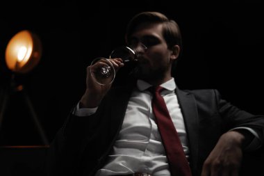 İş adamı dinleniyor. Karanlık bir odada bir bardak şarapla yakışıklı ve zarif bir adamın portresi.