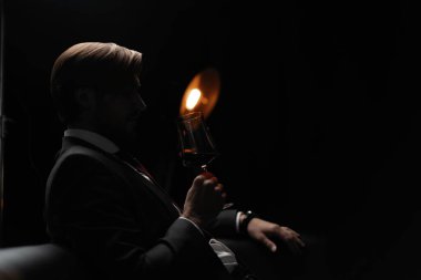 İş adamı dinleniyor. Karanlık bir odada bir bardak şarapla yakışıklı ve zarif bir adamın portresi.