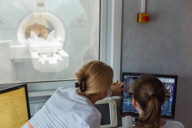 Doktorlar MR odasındaki hastayı muayene ediyor..