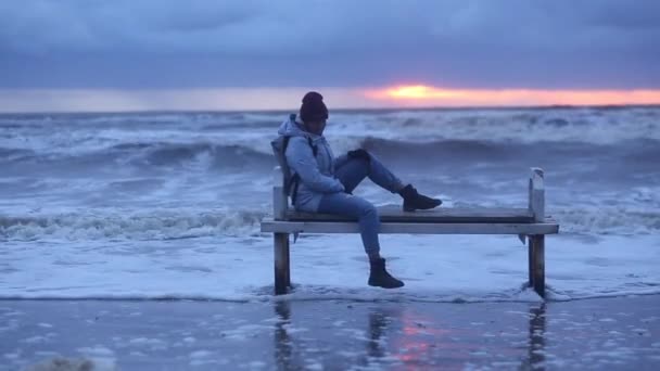 Μοναχικό Κορίτσι Κάθεται Ένα Παγκάκι Δίπλα Στη Θάλασσα Μια Χειμερινή — Αρχείο Βίντεο