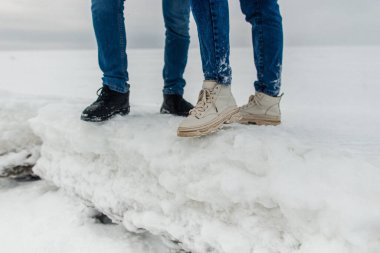 Güzel buz kütlelerinin üzerinde duran çiftleri kucaklayan bacaklar. Deniz kıyısında karlı kış.
