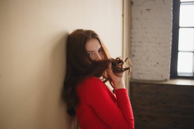 Sade pastel bej arka plan stüdyosunda izole edilmiş kırmızı balıkçı yakalı 20 'li yaşlarda çekici bir kadın. Halk yaşam tarzı konsepti