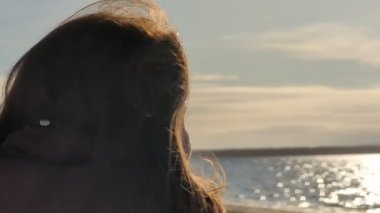 Güzel bir genç kadın güneşli bir günde kış nehrinin arka planında güneş gözlüğü takar. Yüksek kalite 4K görüntü. Yüksek kalite 4k görüntü