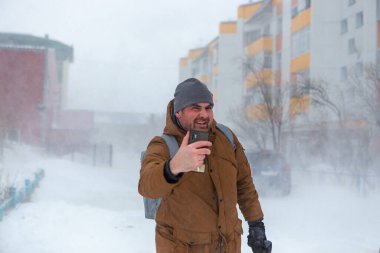 Şiddetli kar fırtınası geliyor. Şiddetli kar fırtınasında görüş mesafesi zayıf. Tehlikeli hava gününde eğlenen adam. Doğanın felaketi. Şehir halkı kar fırtınası konseptinde yaşıyor.
