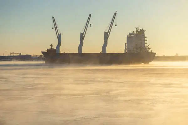 Cargo ship, ice classed bulk carrier in the ice and fog of a freezing river. High quality photo