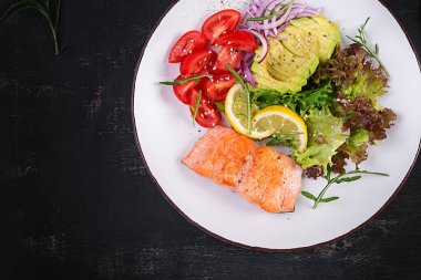 Ketogenik diyet kahvaltısı. Fırında somon salatası, yeşillik, domates, kırmızı soğan ve avokado. Keto, paleo yemeği. Üst görünüm, genel görünüm