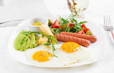 İngiliz kahvaltısı. Yağda yumurta, sosis, domates, avokado, peynir ve zeytin. Amerikan yemekleri..