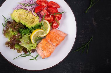 Ketogenik diyet kahvaltısı. Fırında somon salatası, yeşillik, domates, kırmızı soğan ve avokado. Keto, paleo yemeği. Üst görünüm, genel görünüm