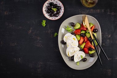 Taze salatalık, domates, burrata peyniri ve zeytinyağlı siyah zeytin salatası. Sağlıklı yiyecekler. Üst manzara, düz uzanma