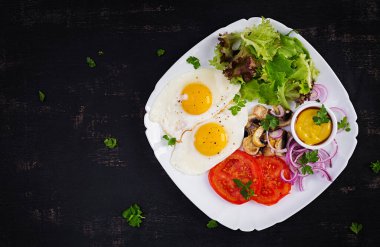 Ketojenik gıda. Yağda yumurta, mantar ve dilimlenmiş domates. Keto, paleo kahvaltısı. Üst görünüm, genel görünüm, kopyalama alanı