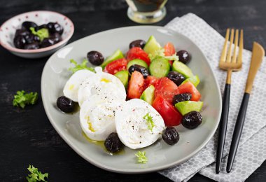 Taze salatalık, domates, burrata peyniri ve zeytinyağlı siyah zeytin salatası. Sağlıklı yemek..