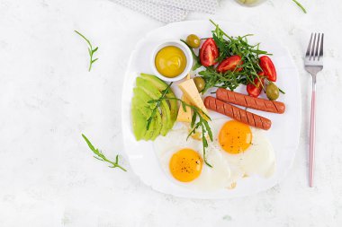 İngiliz kahvaltısı. Yağda yumurta, sosis, domates, avokado, peynir ve zeytin. Amerikan yemeği. Üst görünüm, genel görünüm, kopyalama alanı
