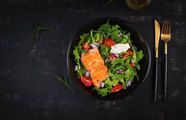 Kızarmış somon balığı filetosu ve krem peynirli taze yeşil marul sebze domates salatası. Üst manzara, düz uzanma