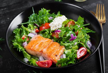 Kızarmış somon balığı filetosu ve krem peynirli taze yeşil marul sebze domates salatası..