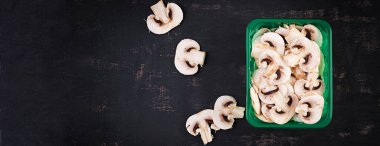 Fresh sliced champignons on a dark background. Top view, banner