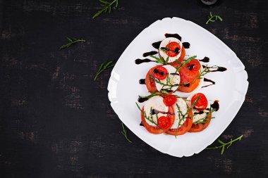 Salad Caprese with tomato, mozzarella and arugula in the shape of a Christmas tree. Top view, overhead