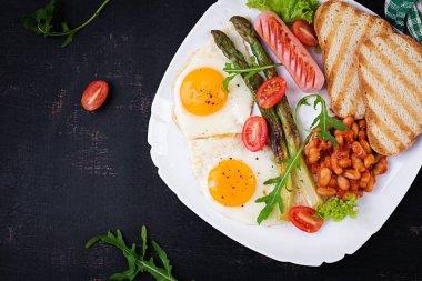 Keto breakfast. Breakfast. Fried eggs, bread toast, green asparagus, beans and sausage on white plate. Top view, flat lay