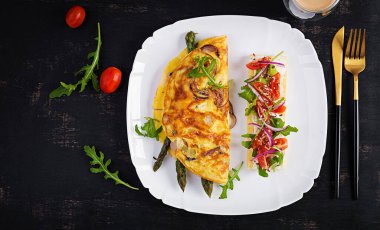 Keto breakfast. Omelette with cheese, red onion and asparagus on dark table. Italian frittata. Keto, ketogenic lunch. Top view, overhead, copy space