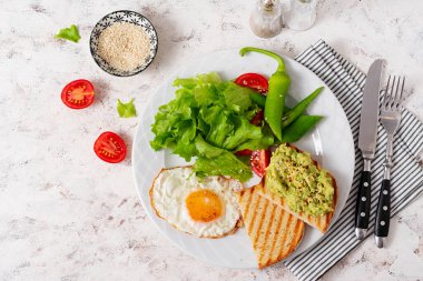 Fried egg, fresh salad and avocado guacamole sandwiches. Top view, concept of a healthy lifestyle