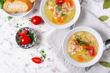 Fish soup with salmon, vegetables and rice in white bowl. Top view, above