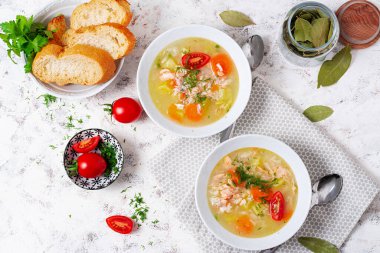 Fish soup with salmon, vegetables and rice in white bowl. Top view, above