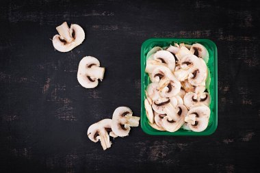Fresh sliced champignons on a dark background. Top view, above