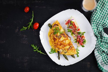 Keto breakfast. Omelette with cheese, red onion and asparagus on dark table. Italian frittata. Keto, ketogenic lunch. Top view, overhead, copy space