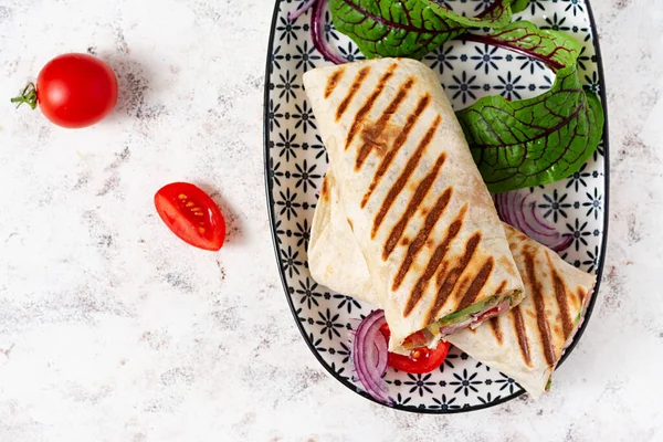 Tortilla wrap with ham, cheese and tomatoes on a white background. Shawarma. Top view, above