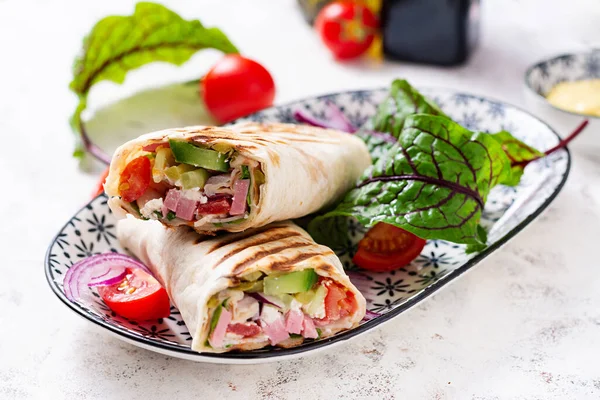 Tortilla wrap with ham, cheese and tomatoes on a white background. Shawarma.