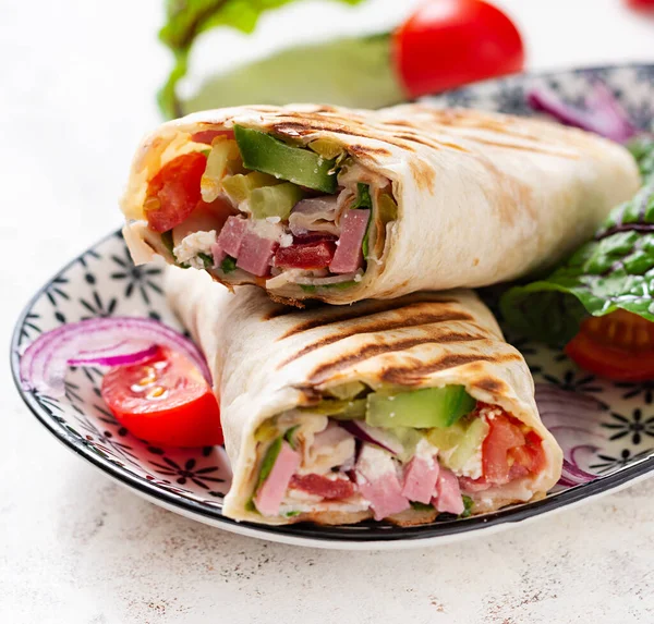 Tortilla wrap with ham, cheese and tomatoes on a white background. Shawarma.
