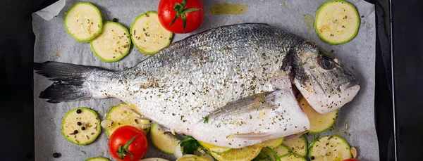 Raw dorado fish with ingredients for making on a baking sheet. Top view, banner
