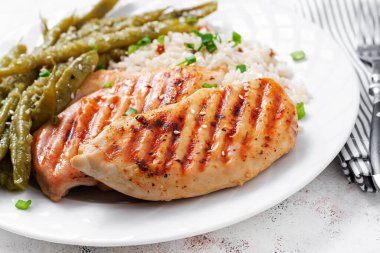 Chicken fillet cooked on a grill and garnish of rice, green beans.